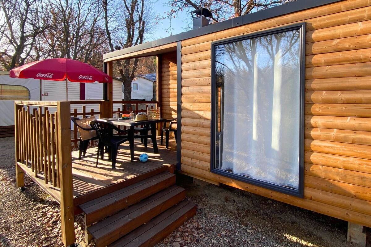 Una cabaña de madera con un balcón, una mesa y sillas.