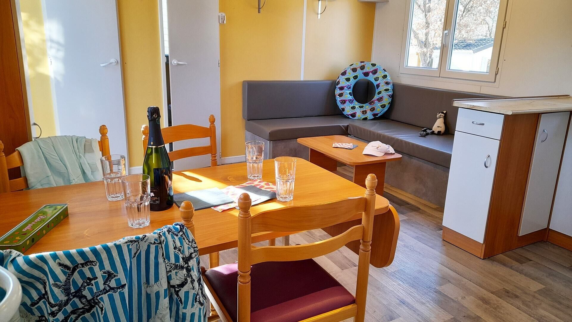 A cozy room with a wooden dining table, chairs, a sofa, and a small kitchenette.