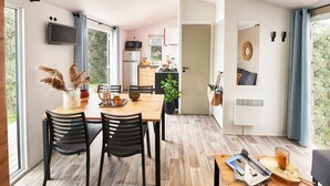 Eine moderne Küche mit Mikrowelle, Herd und Spüle. Es gibt einen Essbereich mit einem Holztisch und Stühlen.