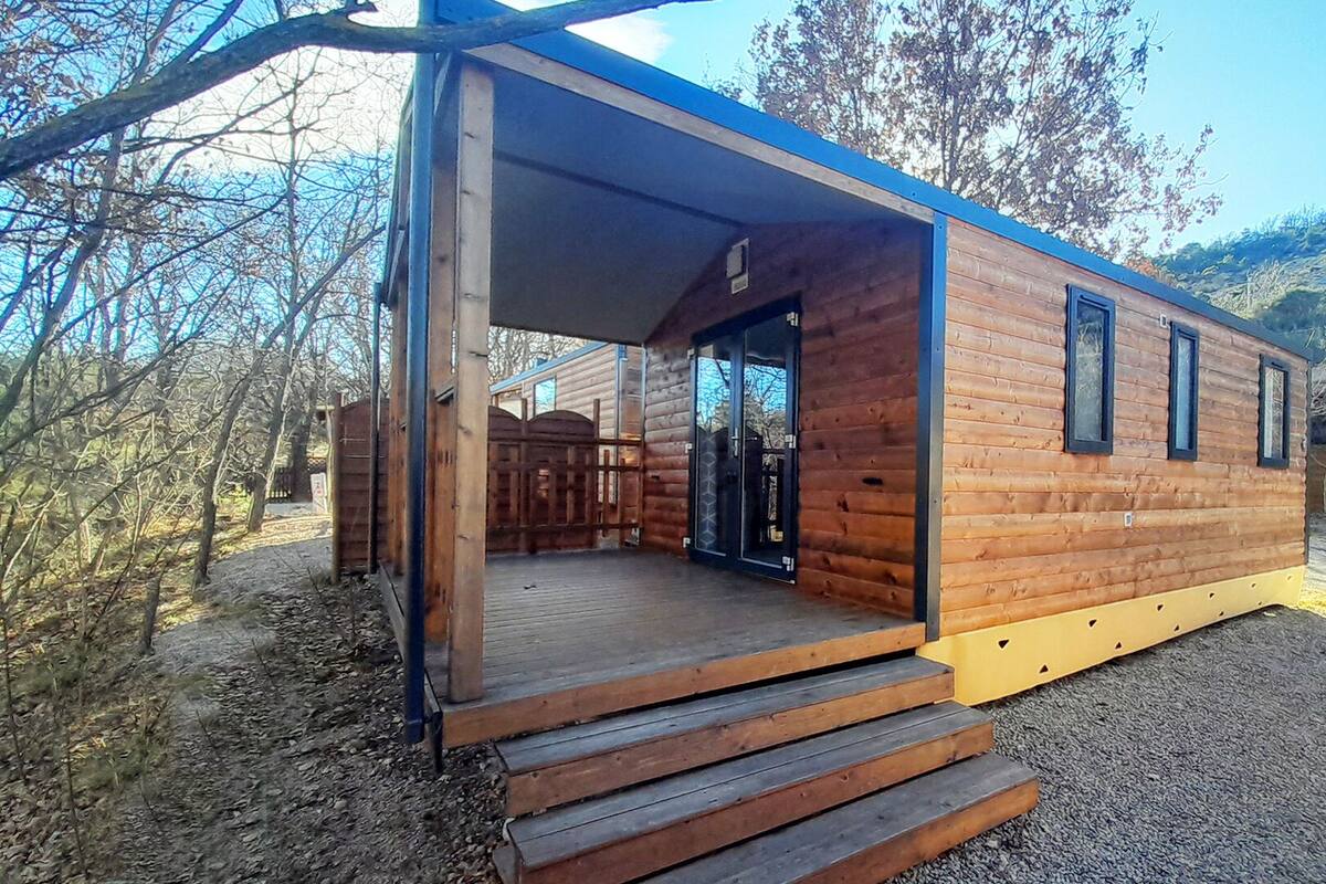 Una cabaña de madera con un porche cubierto, una puerta y una ventana.