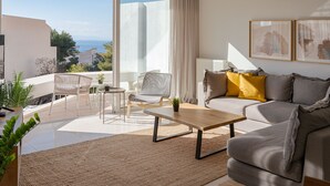 Un soggiorno moderno con divano, tavolino e poltrone. Si apre una grande finestra vista mare.