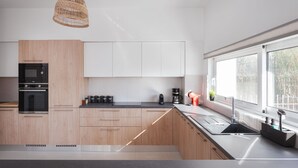 Una cucina moderna con mobili in legno, un forno nero, una macchina per il caffè e una finestra che permette l'illuminazione naturale.