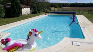 Una piscina con un flotador de unicornio y un niño jugando.