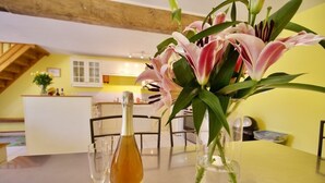 Una mesa de comedor con una botella de vino, dos copas y un jarrón con flores.