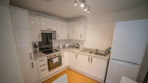 Una cocina moderna con armarios blancos, un lavamanos de acero inoxidable y un horno empotrado.
