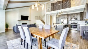 A spacious living area with a wooden dining table, grey upholstered chairs, a fireplace, and a modern kitchen with stainless steel appliances. - Francis Townhome: 5 Mi to Park City Mountain! (Heber City)