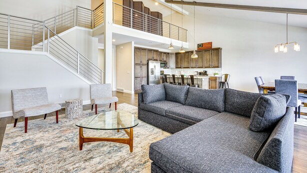 A spacious living area with a large gray sectional sofa, a glass coffee table, and a staircase leading to an upper level. - Francis Townhome: 5 Mi to Park City Mountain! (Heber City)