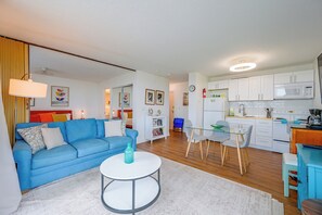 A modern apartment with a blue sofa, a round table, a kitchen with white cabinets, and a dining area. - Fort Myers Beach Studio w/ Balcony & Views! (Fort Myers Beach)