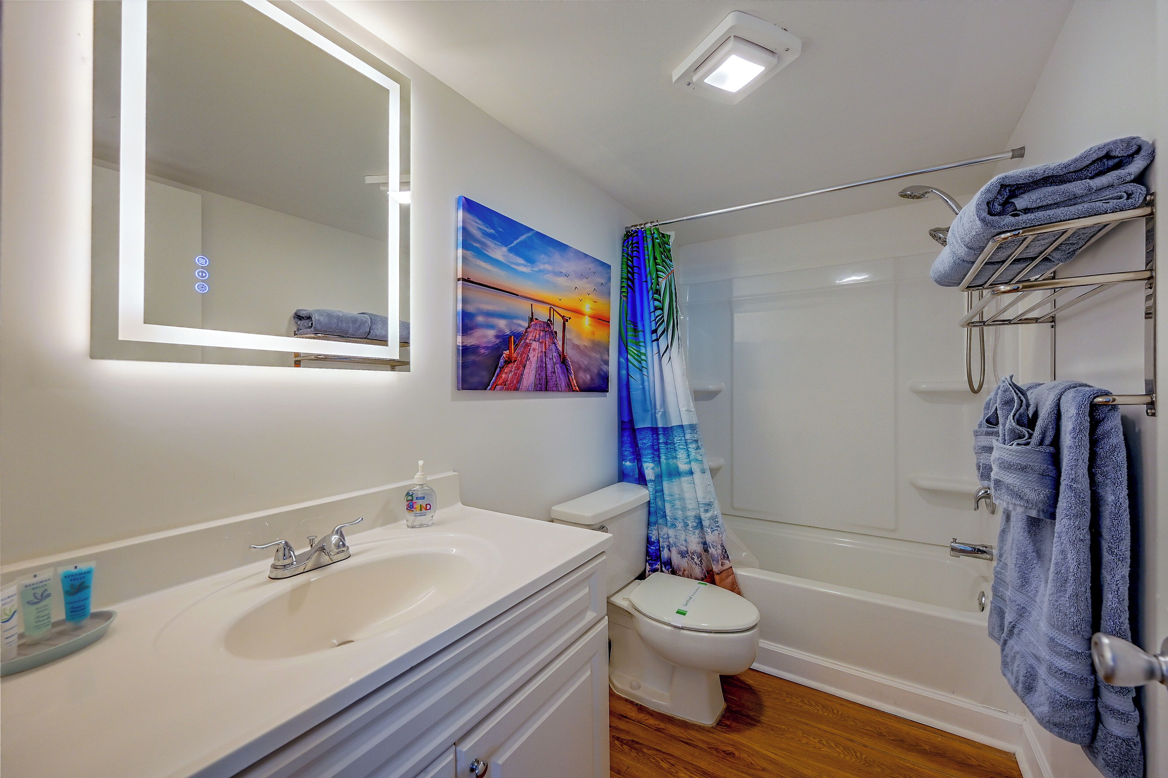 Une salle de bain avec un lavabo blanc, des toilettes, une douche avec un rideau bleu et un porte-serviettes.