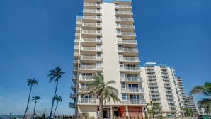 Un hôtel de grande hauteur doté de nombreux balcons, d’une entrée principale et offrant une vue sur la plage.
