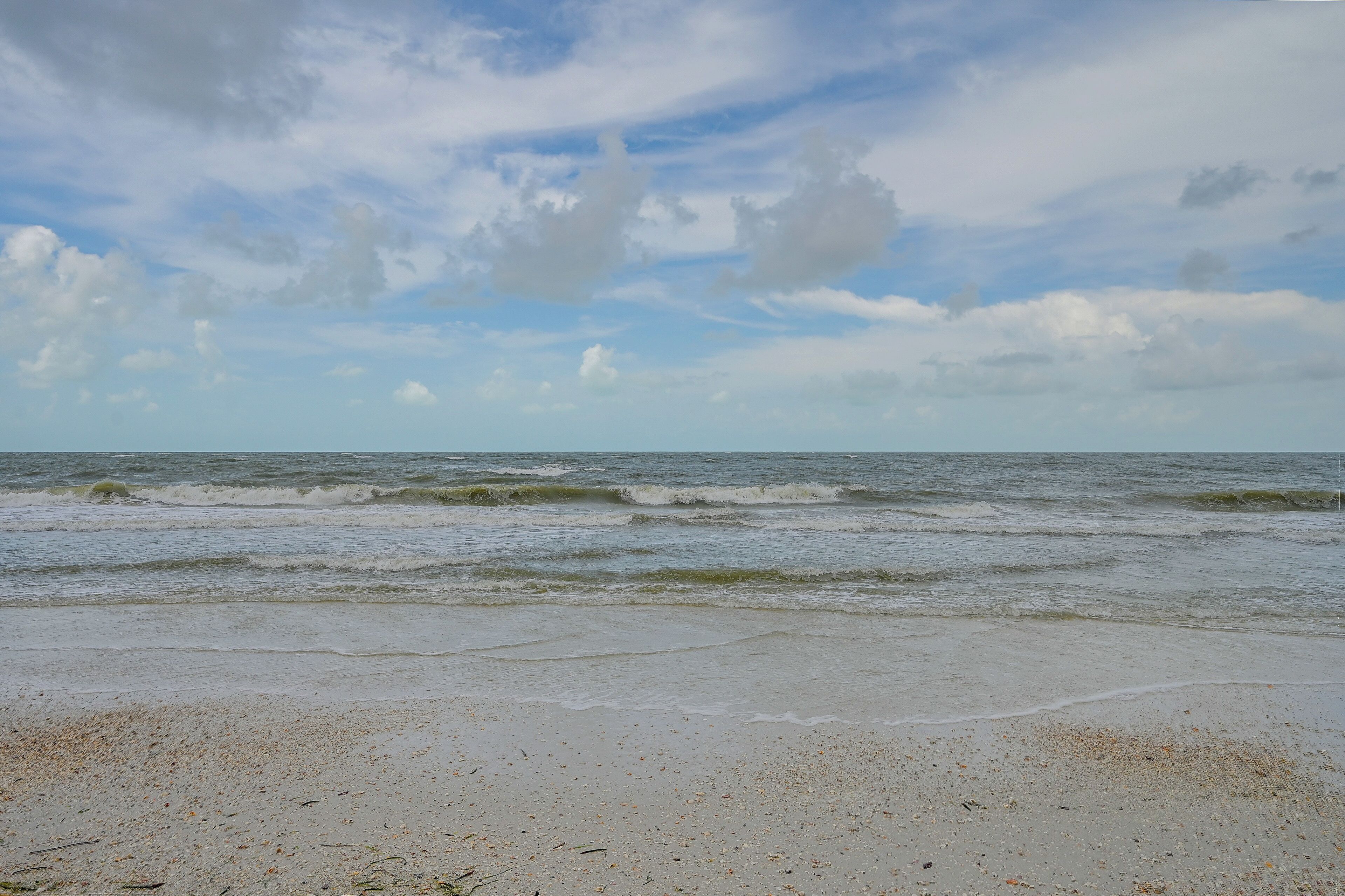 Une plage avec des vagues et un ciel nuageux.