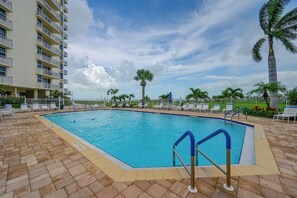 A swimming pool with a clear blue water, surrounded by lounge chairs and palm trees. - Fort Myers Beach Studio w/ Balcony & Views! (Fort Myers Beach)