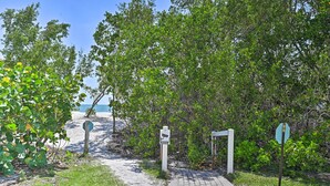 Un sentier menant à une plage, avec un panneau indiquant l’entrée de la plage.