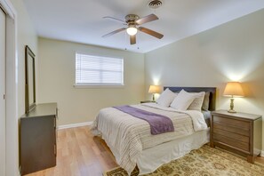 A bedroom with a bed, bedside lamps, a ceiling fan, a window with blinds, a dresser, and a patterned rug. - 5 Mi to City Park: New Orleans Area Home (Metairie)