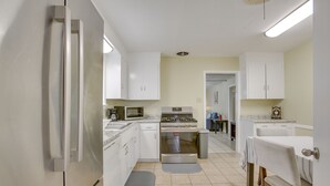 Una cocina con armarios blancos, estufa, microondas y refrigerador.