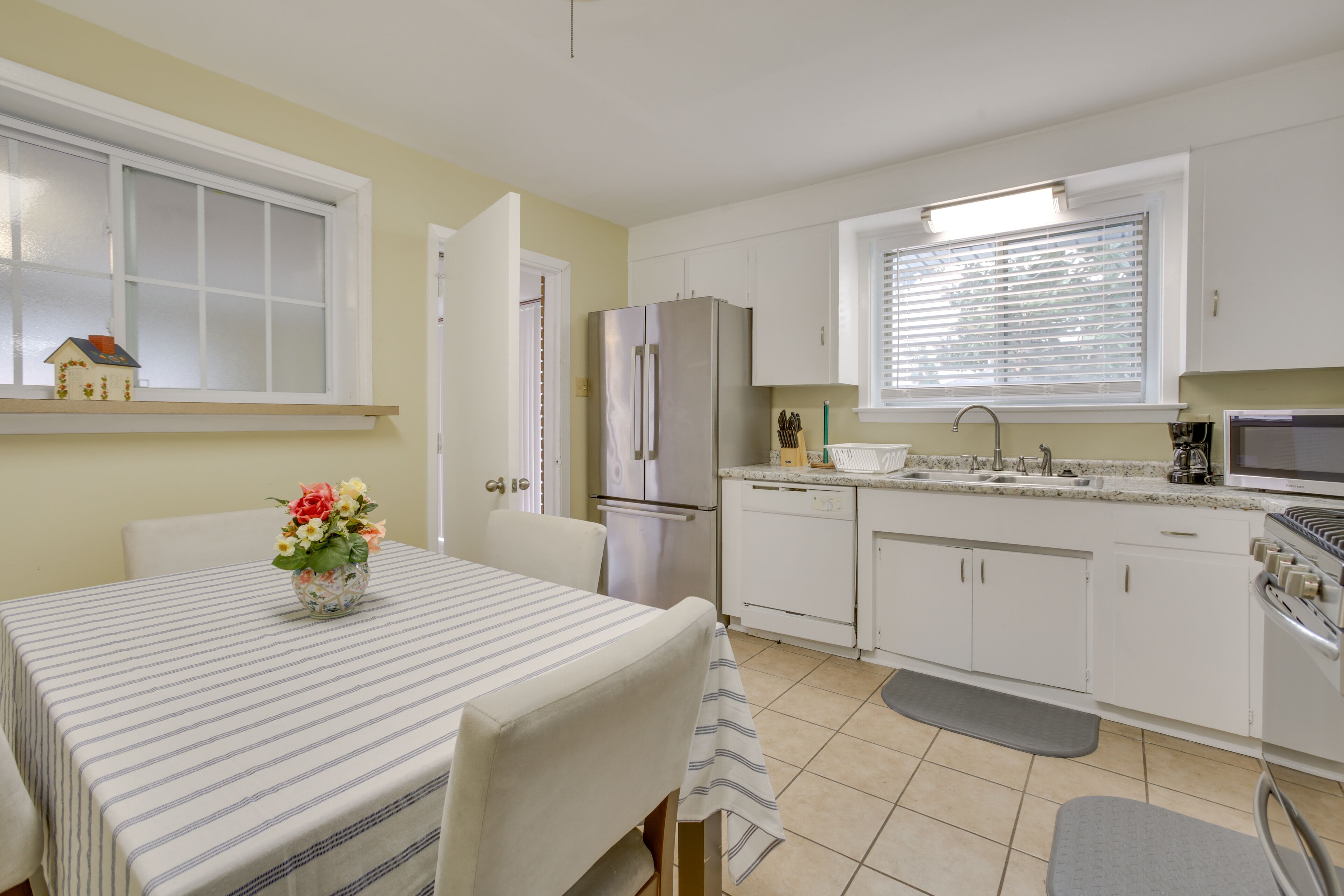 A modern kitchen with white cabinets, a stainless steel refrigerator, a microwave, and a sink.