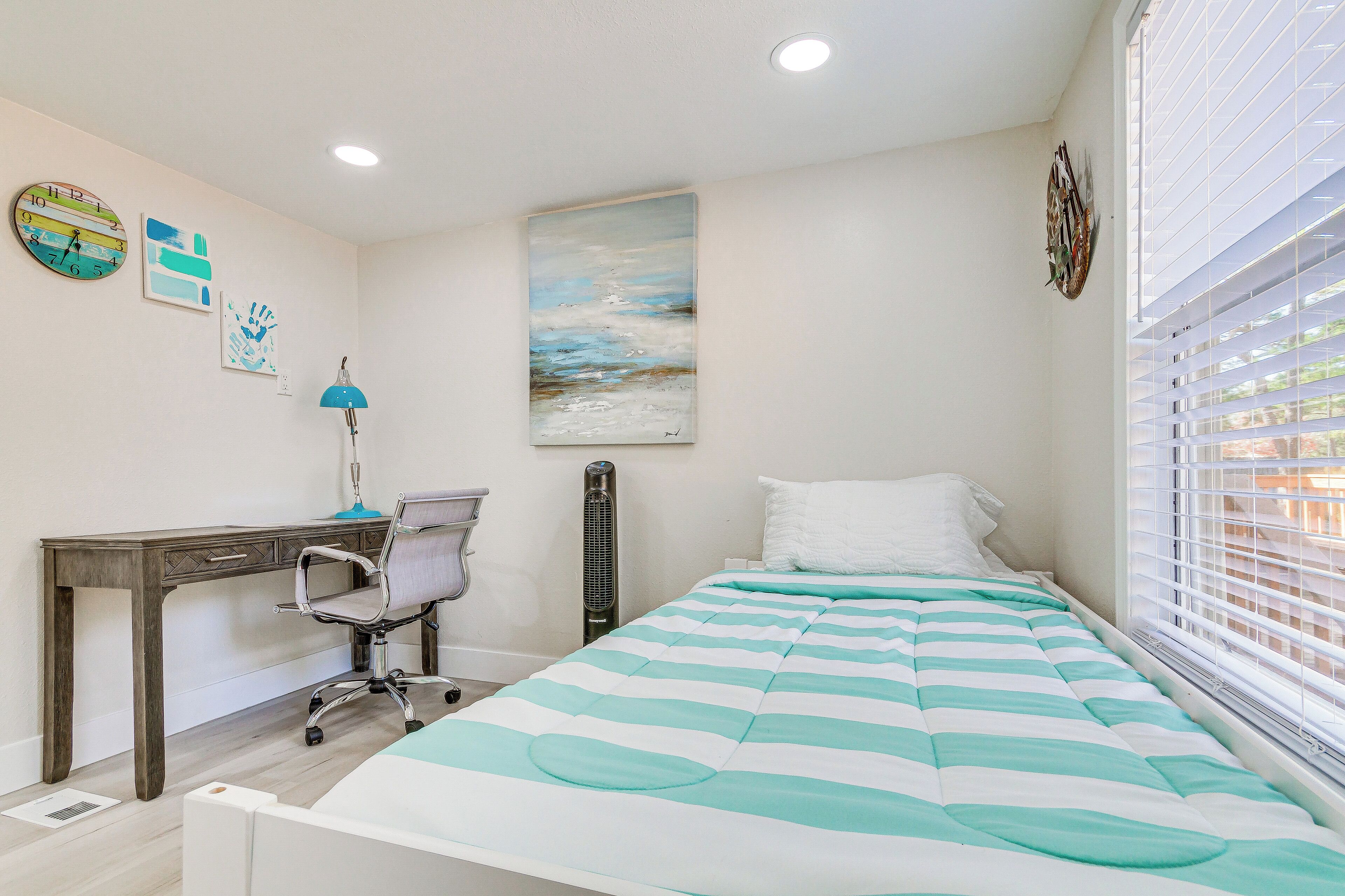Une chambre à coucher comprenant un lit, un bureau, une chaise, une lampe, un radiateur et une fenêtre avec des stores.