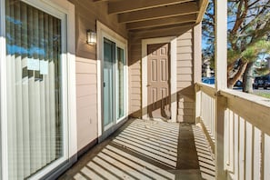 A wooden porch with a door and window blinds.