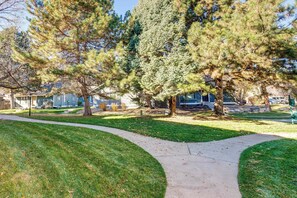 A park with a curved pathway, large trees, and a building in the background.
