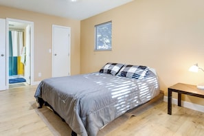 A bedroom with a bed, a bedside table with a lamp, a window, and a door leading to a bathroom. - Englewood Condo w/ Pool Access: 1 Mi to Light Rail (Englewood)