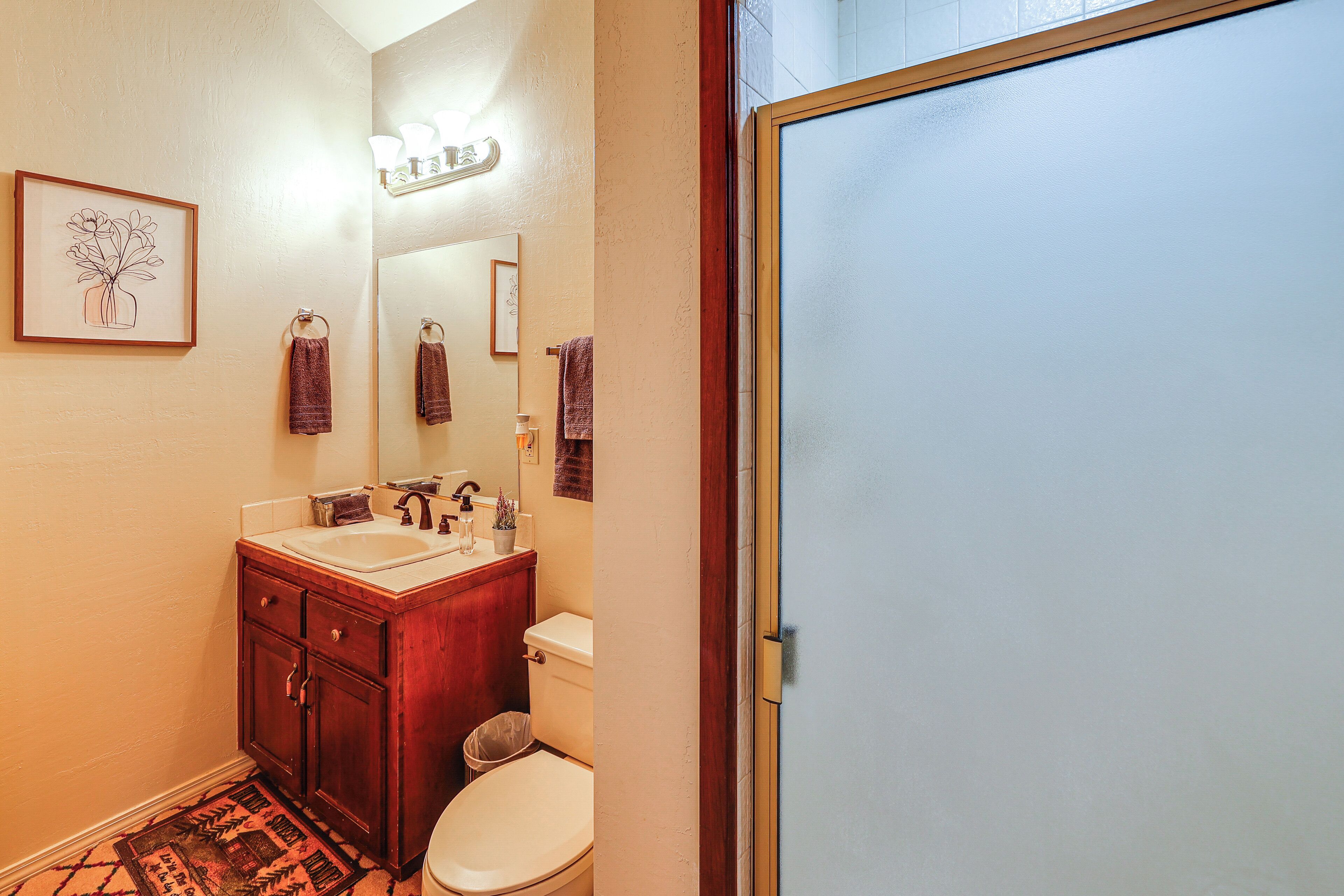 A bathroom with a wooden vanity, a white toilet, and a mirror above the sink.