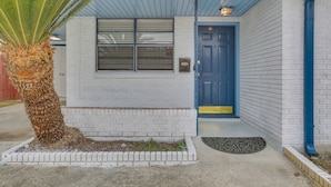 A building with a blue door, a window, and a small palm tree in front. - 5 Mi to City Park: Charming Home Near Nola! (Metairie)