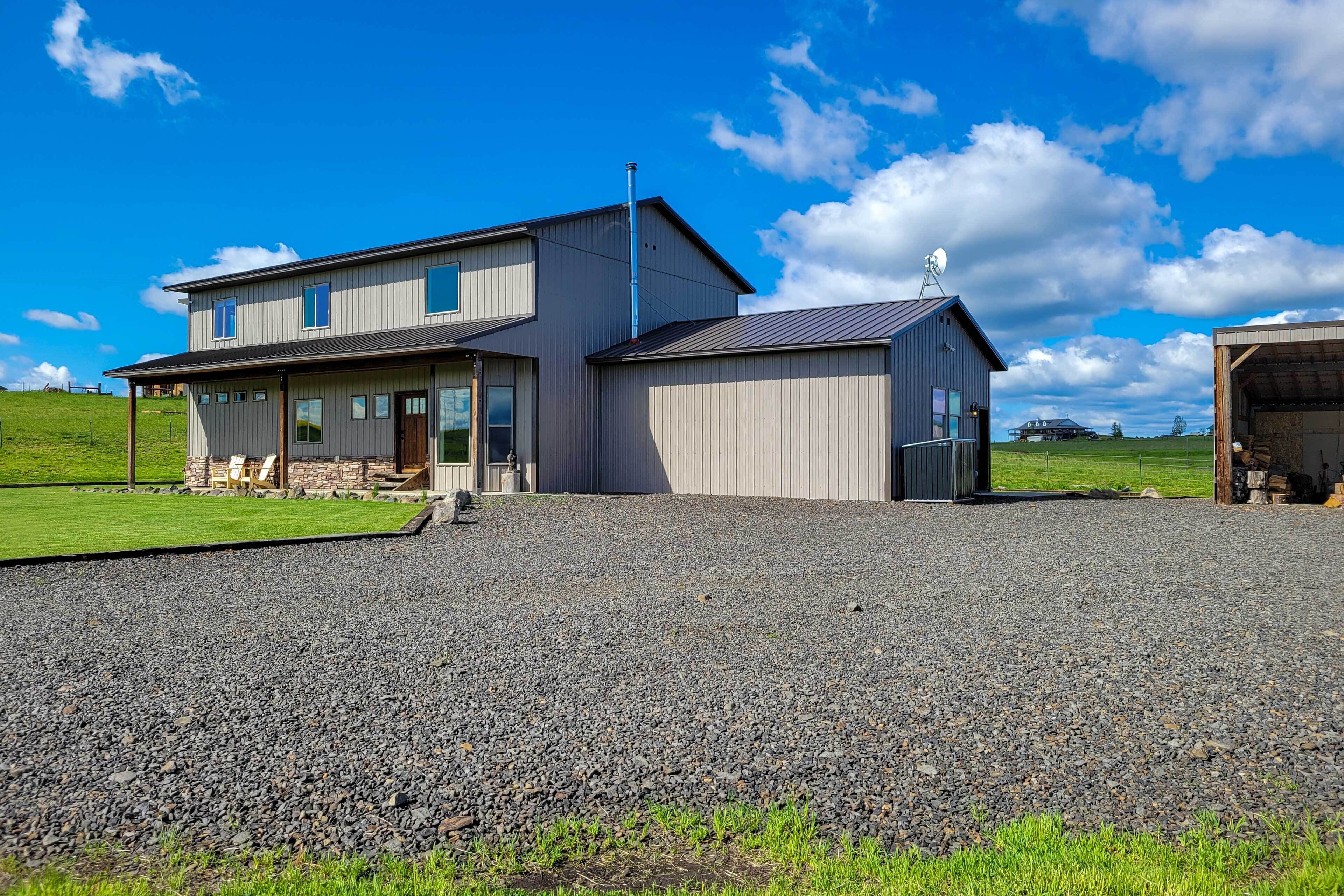 A two-story house with a gravel driveway and a green lawn.