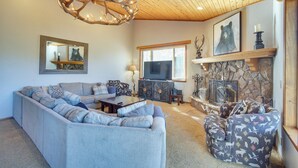 A living room with a large sectional sofa, a fireplace, and a deer antler chandelier. - Big Bear Lake Cabin w/ Hot Tub & Gas Fire Pit! (Big Bear Lake)