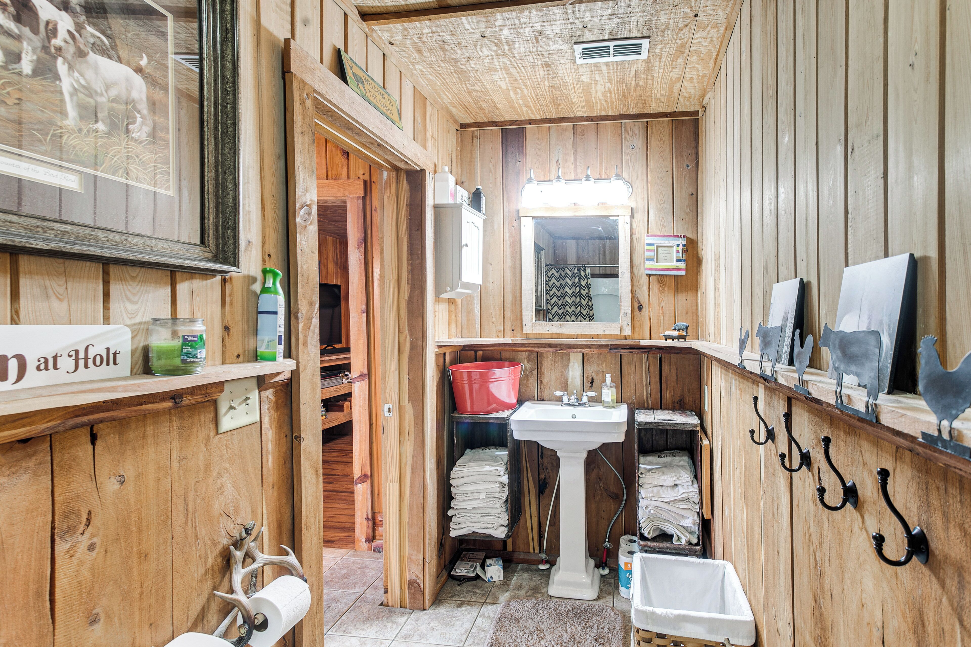 A wooden bathroom with a sink, mirror, and towel rack.