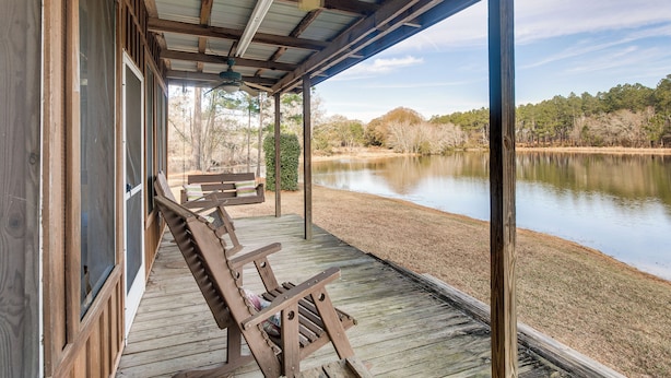 A covered porch with wooden benches overlooking a lake.