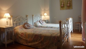 A bedroom with two beds, each with a headboard and bedside tables. There are lamps on the tables, and a painting on the wall. - Agréable Maison en Pierres, à Quelques Minutes des Châteaux (vézac)