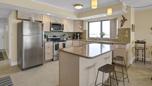 A modern kitchen with a large island, stainless steel appliances, and pendant lighting.
