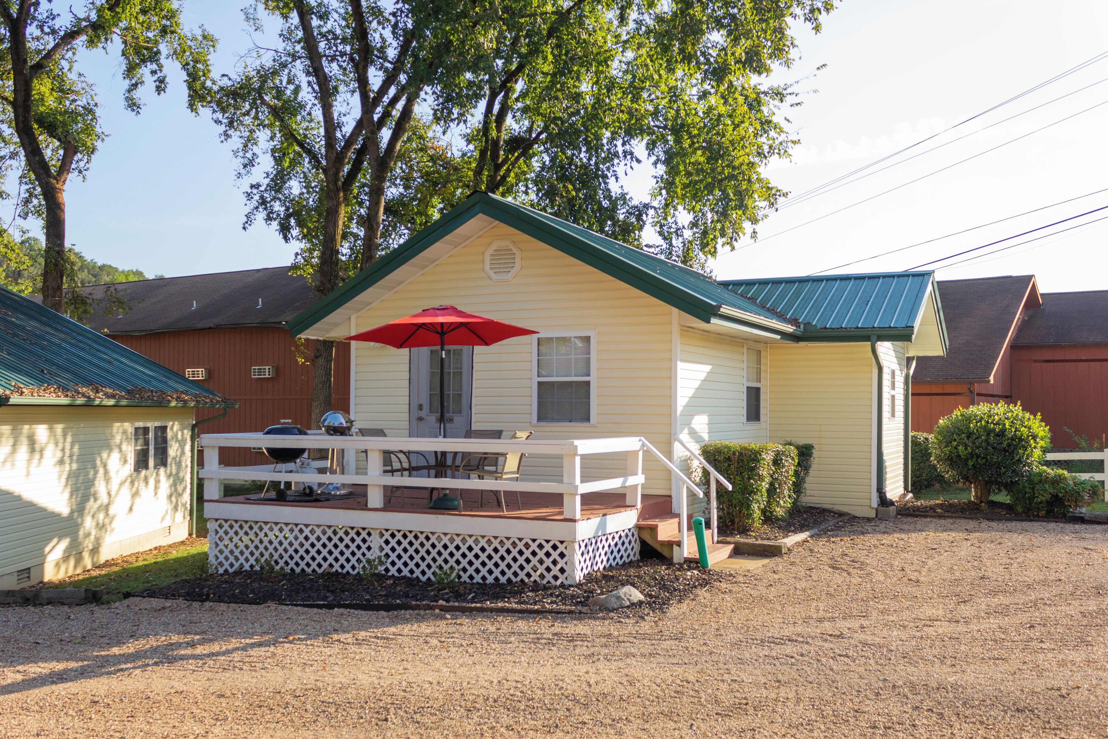 A small, single-story house with a porch and a red umbrella.