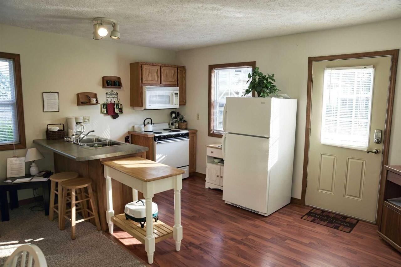 A compact kitchen with wooden cabinets, a white refrigerator, and a small island with stools.