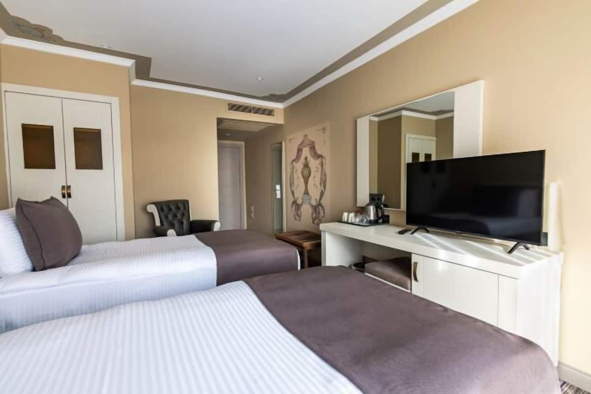 A hotel room with two beds, a television, a desk, and a chair.
