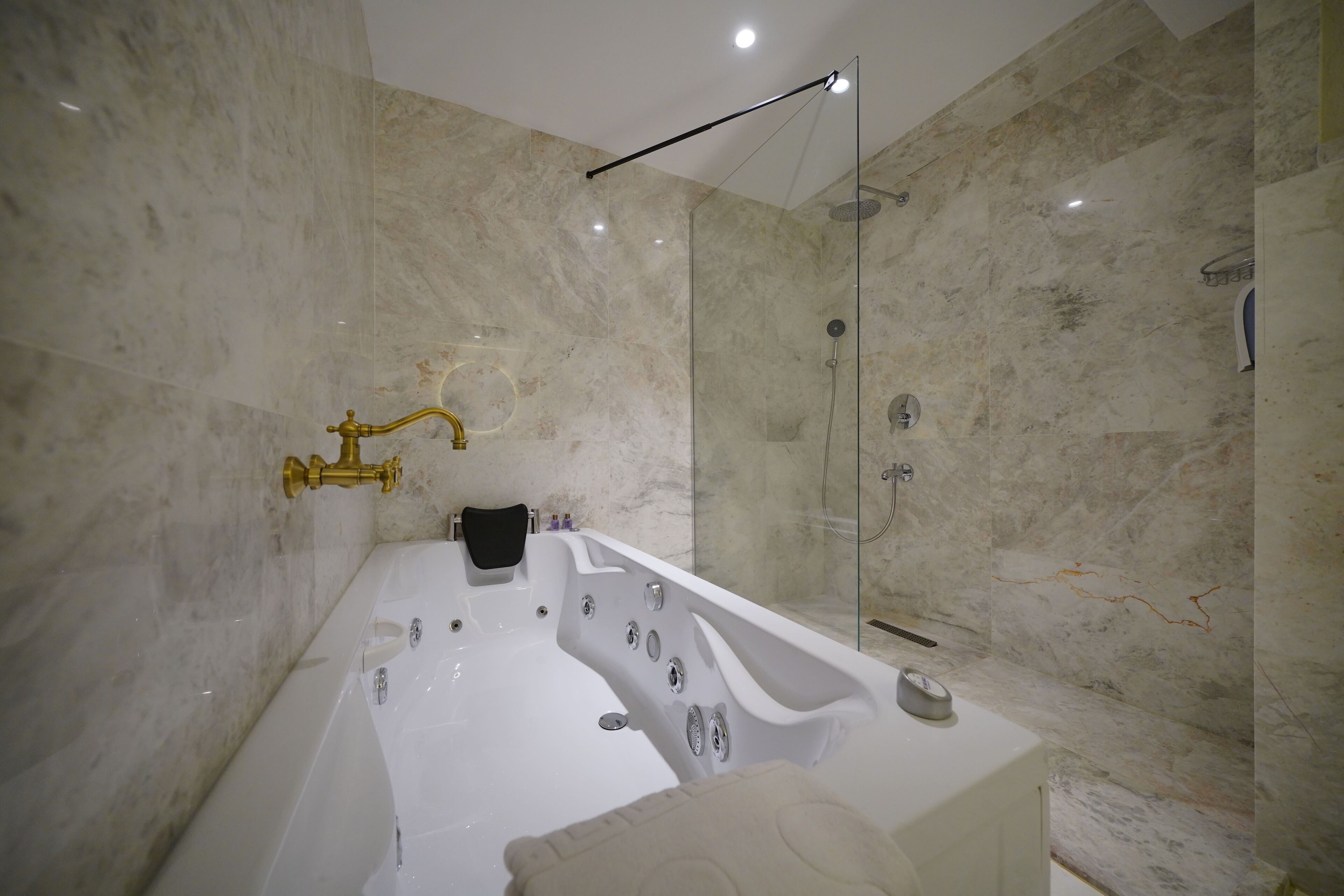 Un baño moderno con una bañera amplia, una ducha con cerramiento de vidrio y paredes de mármol.
