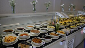 A buffet with various food items and small vases with white flowers on the counter. - Zemi Hotel Cappadocia (Nevsehir)