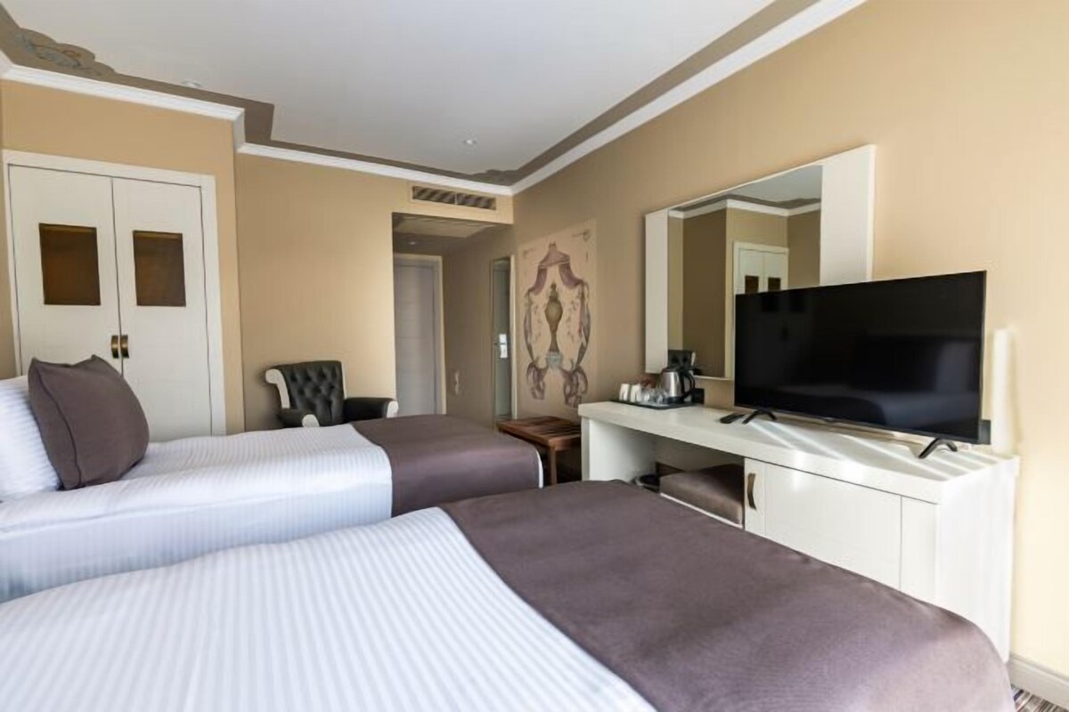 A hotel room with two beds, a television, a desk, and a chair.