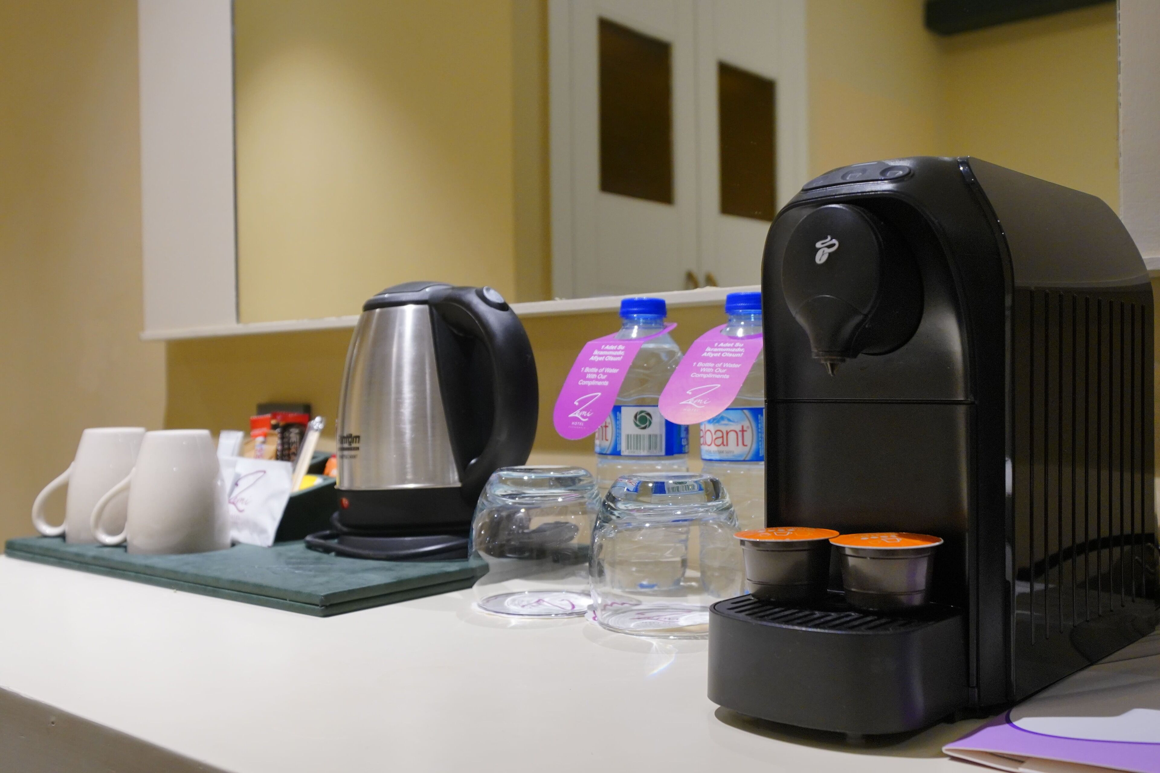 Una cafetera, dos tazas, dos botellas de agua y un hervidor sobre una encimera.