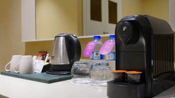 Una cafetera, dos tazas, dos botellas de agua y un hervidor sobre una encimera.