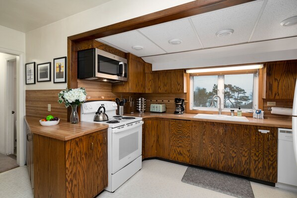 Una cocina moderna con armarios de madera, microondas integrado, estufa y ventana que proporciona luz natural.