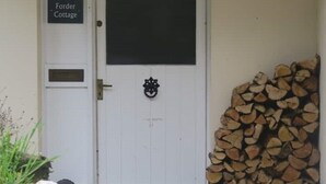 A white door with a black window and a sign reading "Forder Cottage".