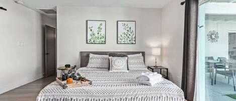 A modern bedroom with a wooden bed, a ceiling fan, and two framed botanical prints on the wall.