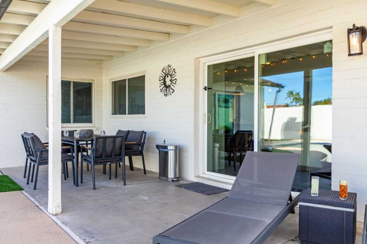 Eine Terrasse im Freien mit Tisch und Stühlen, einem Liegestuhl und einem Mülleimer.