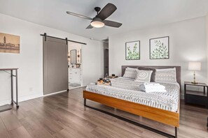 A modern bedroom with a bed, a ceiling fan, a nightstand, and artwork on the walls. - Greenway Getaway - Private Pool - North Scottsdale (Scottsdale)