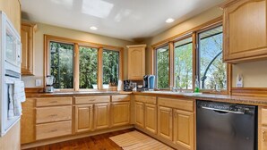 A kitchen with wooden cabinets, a dishwasher, and large windows.