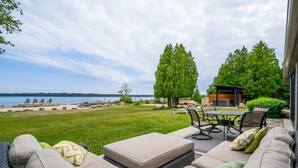 A patio with outdoor furniture, a view of the beach, and a lake.