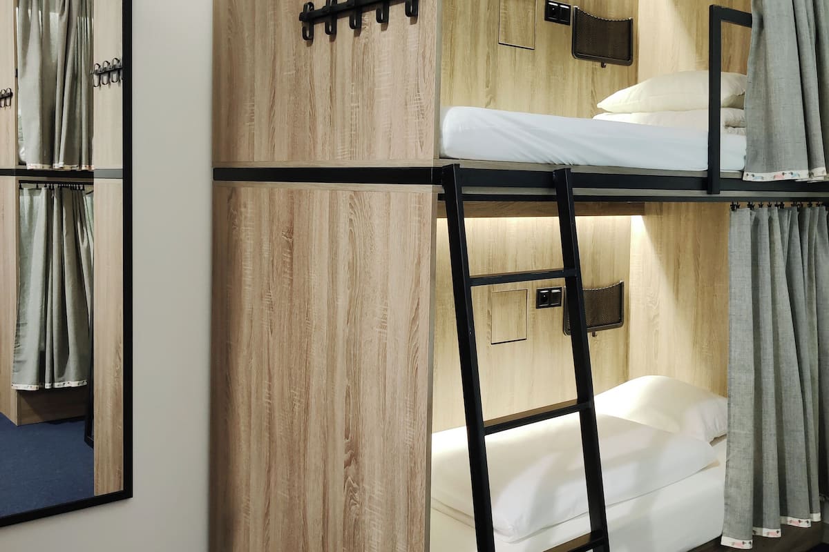 A bunk bed room with wooden walls, a small shelf, and a mirror.