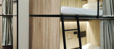 Dormitorio con literas, paredes de madera, un estante pequeño y un espejo.