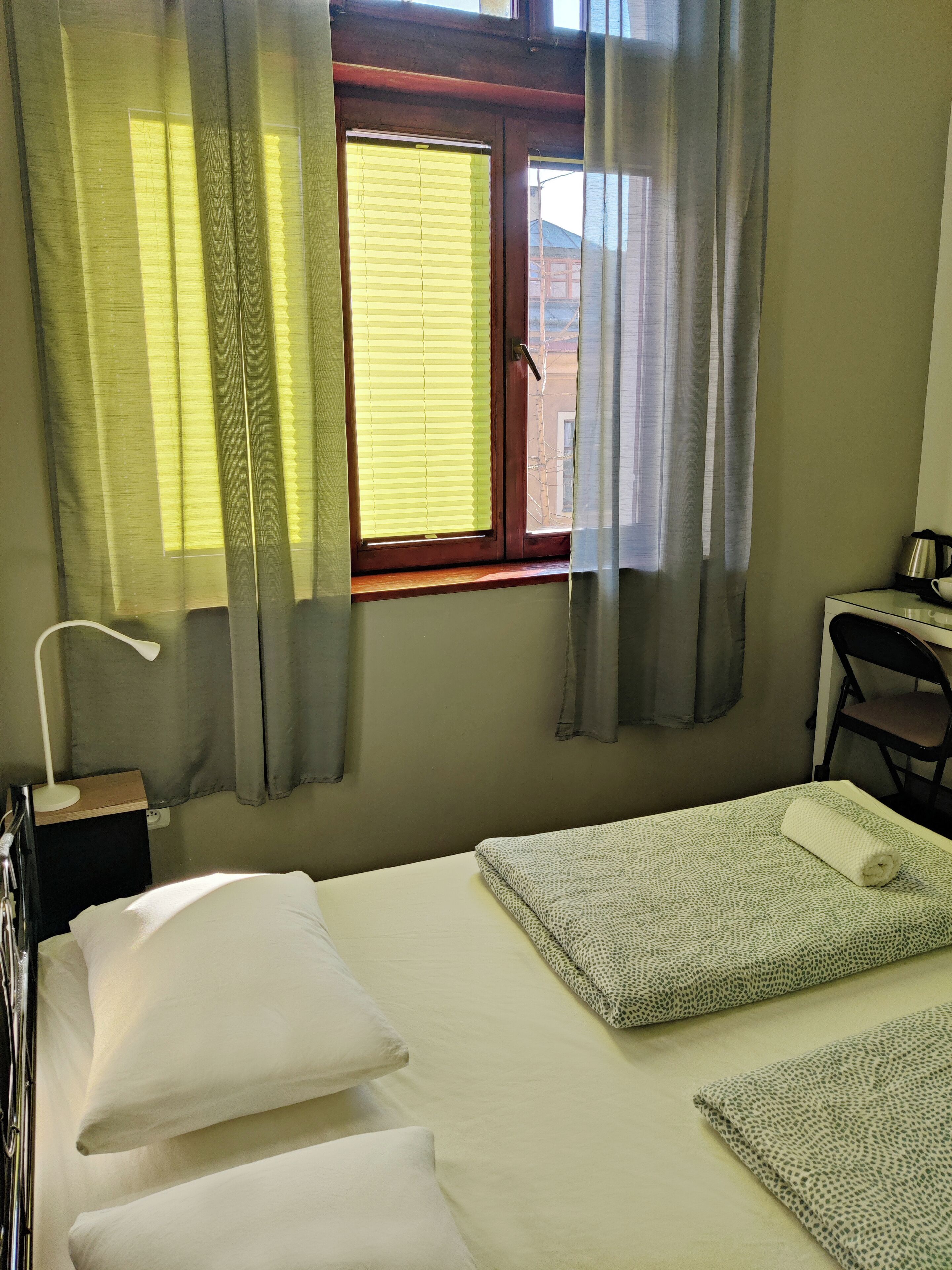 Un dormitorio con cama, escritorio y ventana con cortinas.